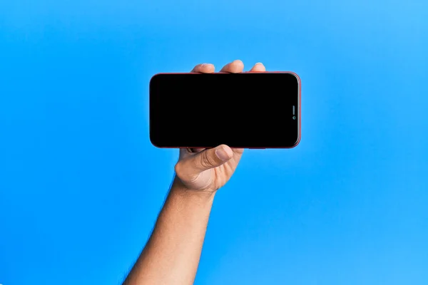 Mano Joven Hispano Mostrando Smartphone Sobre Fondo Azul Aislado —  Fotos de Stock