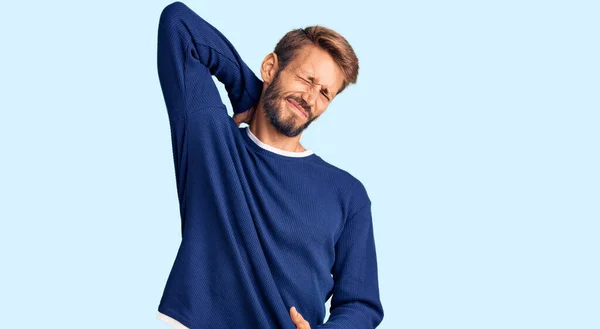 턱수염을 기르고 가벼운 스웨터 손으로 만지고 근육통을 호소하는 잘생긴 금발의 — 스톡 사진