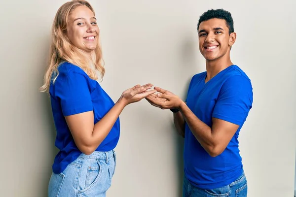 若い異人種間のカップルは コピースペースを示す手を開いて手のひらで脇を指してカジュアルな服を着て 広告を提示笑顔興奮幸せ — ストック写真