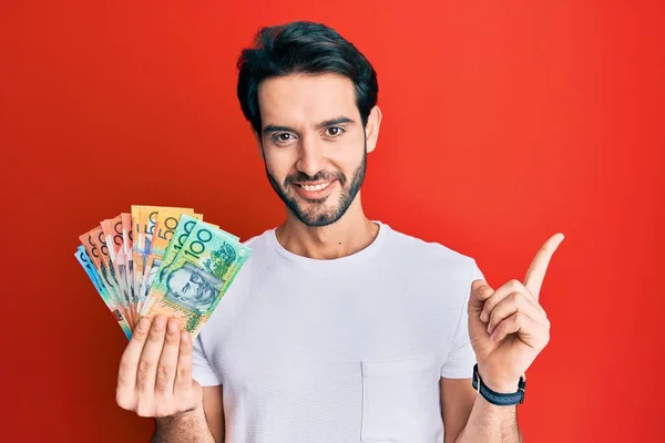 Ung Latinamerikan Man Håller Australiska Dollar Ler Glad Pekar Med — Stockfoto