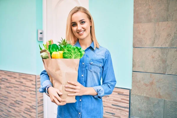 Joven Chica Rubia Sonriendo Feliz Sosteniendo Comestibles Bolsa Papel Pie —  Fotos de Stock