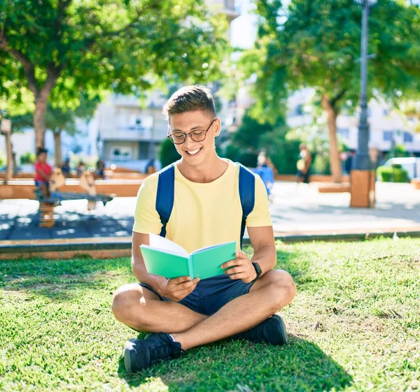 他那恐慌的年轻学生坐在大学校园的草地上看书 — 图库照片
