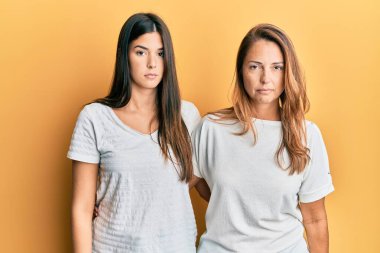 Gündelik beyaz tişört giyen İspanyol anne ve kız ailesi ciddi bir ifadeyle rahatladı. Basit ve doğal bir şekilde kameraya bakıyorsun.. 
