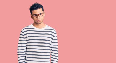 Gündelik kıyafetler giyen, gözlüklü, şüpheci ve gergin, sorun yüzünden surat asan İspanyol asıllı yakışıklı bir genç. negatif kişi. 