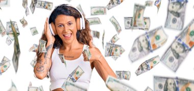 Dövmeli, müzik dinleyen, kulaklık takan mutlu ve olumlu gülümseyen genç İspanyol kadın.