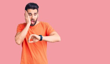 Sakallı, sıradan tişörtlü genç yakışıklı. Saate bakıyor. Endişeli, geç kalmaktan korkuyor. 