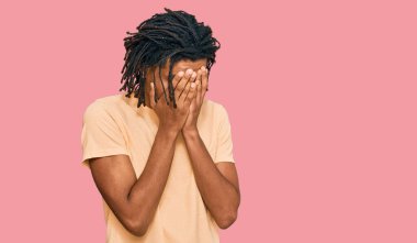 Genç, Afro-Amerikan bir adam, günlük kıyafetler giyiyor ve ağlarken suratını ellerle kapatıyor. depresyon kavramı. 