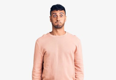 Günlük kıyafetler giyen genç İspanyol adam komik yüzlü yanakları şişiriyor. Havayla şişmiş ağız, çılgın bir ifade.. 