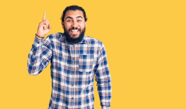 Gündelik giysiler giymiş genç bir Arap başarılı bir fikirle işaret ediyor. Heyecanlı ve mutlu. Bir numara.. 