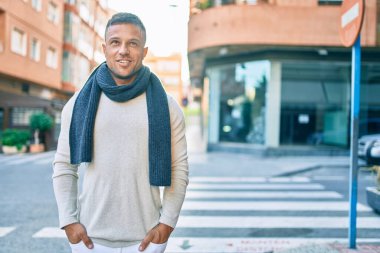 Genç beyaz adam gülümseyerek şehirde mutlu mesut yürüyor..