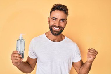 Genç İspanyol adam el dezenfektanı jeli kullanıyor gururla bağırıyor, zaferi ve başarıyı kutluyor. 