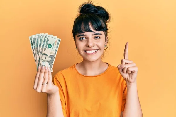 Young Hispanic Girl Holding Dollars Smiling Idea Question Pointing Finger — Stock Photo, Image