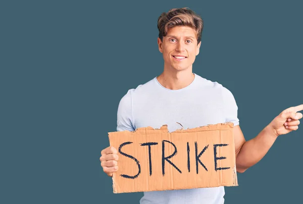 Young Handsome Man Holding Strike Banner Cardboard Smiling Happy Pointing — Stock Photo, Image