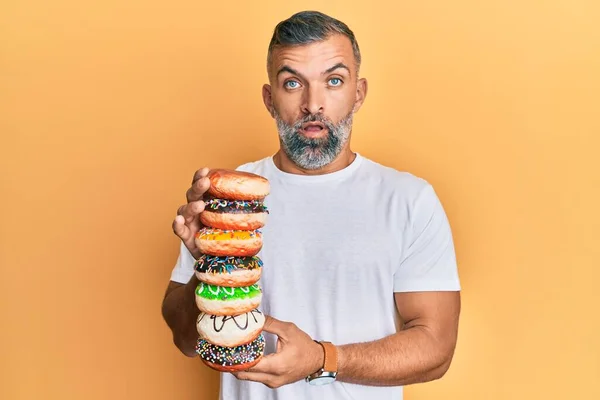 Hombre Guapo Mediana Edad Sosteniendo Sabrosas Rosquillas Colores Cara Choque —  Fotos de Stock