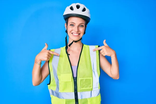 Young caucasian girl wearing bike helmet and reflective vest looking confident with smile on face, pointing oneself with fingers proud and happy.