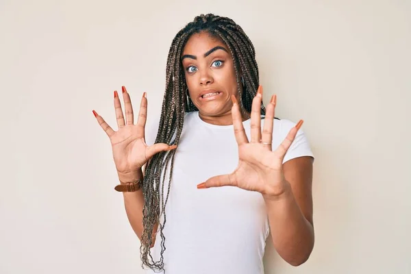 カジュアルな白いTシャツを着た若いアフリカ系アメリカ人の女性は 手で恐怖表現のジェスチャーを停止し ショックで叫んで恐れている パニックの概念 — ストック写真