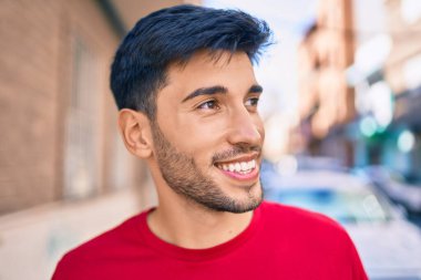 Genç Latin adam gülümseyerek şehirde mutlu mesut yürüyor..