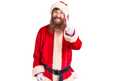 Uzun sakallı, yakışıklı kızıl saçlı Noel Baba kostümü giyen bir numaralı parmağını gösterip gülümseyen, kendinden emin ve mutlu bir adam.. 