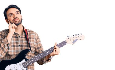 Elektro gitar çalan genç bir İspanyol. Ciddi bir yüz ifadesi. Elleri çenesinde soru sormayı düşünüyor. 