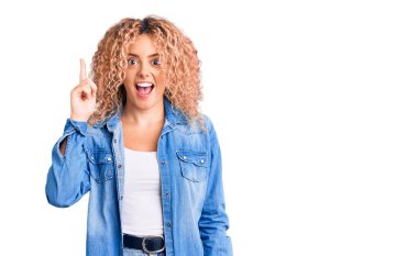 Kıvırcık saçlı, sıradan kot ceket giyen genç sarışın kadın başarılı bir fikir için parmağını kaldırdı. Heyecanlı ve mutlu. Bir numara.. 