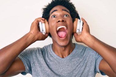 Yakışıklı Afro saçlı, müzik dinleyen kulaklık takan sinirli ve öfkeli sinirli sinirli sinirli bağıran öfkeyle bağıran afro-amerikalı adam.. 