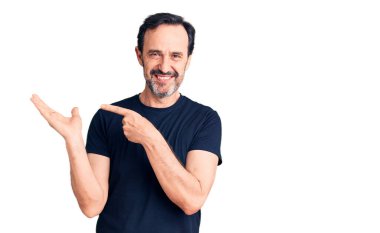 Sıradan tişörtler giyen orta yaşlı yakışıklı adam kameraya hayret ediyor ve gülümsüyor.. 