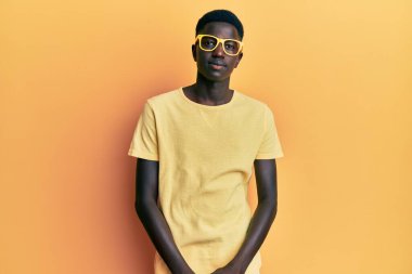 Sıradan kıyafetler ve gözlük takan genç Afro-Amerikan adam yüzünde ciddi bir ifadeyle rahatladı. Basit ve doğal bir şekilde kameraya bakıyorsun.. 