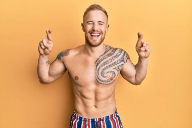 Mayo giyen genç, beyaz bir adam parmaklarını çapraz yapıp umut ve gözleri kapalı gülümsüyor. Şans ve batıl inançlar. 