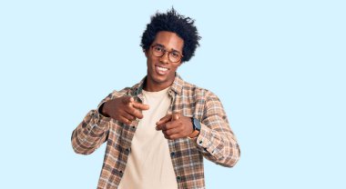 Afro saçlı, sıradan giyinmiş ve gözlüklü, neşeli ve komik yüzüyle kamerayı işaret eden yakışıklı Afro Amerikalı adam. iyi enerji ve titreşimler. 