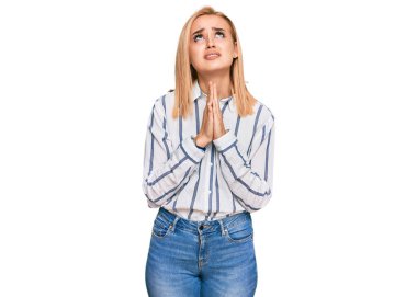 Güzel, beyaz bir kadın, günlük giysiler giyip elleri bağlı yalvarıyor ve dua ediyor. Yüzünde umut ifadesi var. Çok duygusal ve endişeli. Yalvarıyor. 
