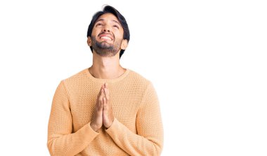 Yakışıklı İspanyol kazak giyen, elleri bağlı yalvaran, dua eden yüzünde umut ifadesi olan çok duygusal ve endişeli bir adam. Yalvarıyor. 