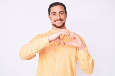 Gündelik kıyafetler giyen, aşık bir genç adam. Elleriyle kalp sembolü ve şekli gösteriyor. romantik kavram. 