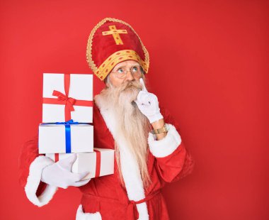 Gri saçlı ve uzun sakallı yaşlı bir adam Aziz Nicholas kostümü giyiyor. Ciddi bir yüz ifadesi var. Çene üstüne el sorusu, kafa karıştırıcı bir fikir. 