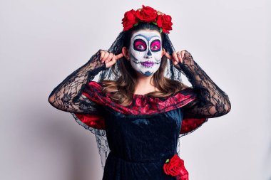 Ölü kostümü giymiş genç bir kadın beyazların üzerine gülüyor kulakları parmaklarıyla çekiyor, komik bir jest. deneme sorunu 