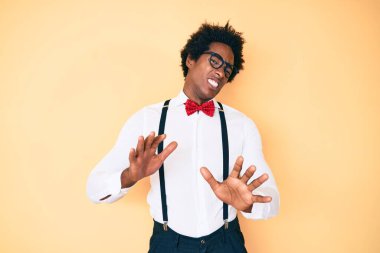 Afro saçlı yakışıklı Afro-Amerikan bir adam. Zarif görünümlü, tiksindirici ve tiksindirici bir ifade takınıyor. Çünkü tiksinti tepkisi veriyor. Eller havada. 