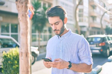Şehirde akıllı telefon kullanan ciddi bir suratı olan genç bir İspanyol..