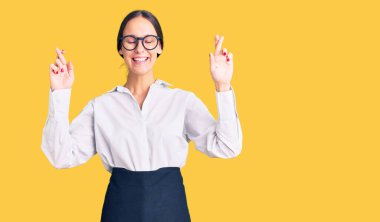 Güzel, esmer, profesyonel garson önlüğü giyen, umut ve gözlerin kapalı bir şekilde gülümseyerek el hareketi yapan genç bir kadın. Şans ve batıl inançlar. 