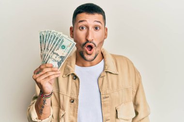 Elinde 20 dolarlık banknotlar tutan yakışıklı bir adam ağzı açık kalmış, korkmuş ve hayrete düşmüş. 