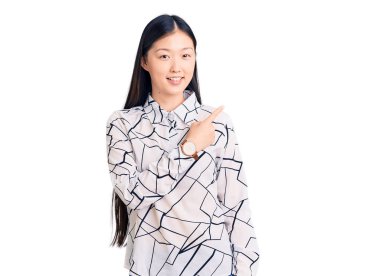 Genç, güzel, Çinli bir kadın. Neşeli tişörtler giyiyor. Yüzünde gülümseme var. 