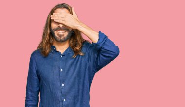 Uzun saçlı, sakallı, sıradan kıyafetler giyen, gülümseyen ve gülen, gözlerini kapatan çekici bir adam. kör kavram. 