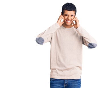 Genç Afro-Amerikan bir adam gündelik kıyafetler giyip yüksek sesli müzik sesi için kulaklarını parmaklarıyla kapatıyor. sağır kavramı. 