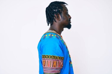 Örgülü, geleneksel Afrika tişörtü giyen, rahat bir görünüm takınan, kendine güvenen gülümseyen Afro-Amerikalı genç bir adam.. 