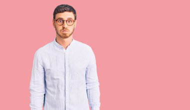 Zarif iş gömleği giyen, gözlüklü, komik suratlı yakışıklı genç adam. Havayla şişmiş ağız, çılgın bir ifade.. 