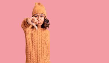 Genç, güzel, melez, yün kazak giyen, kışlık şapkalı, mutsuz görünen, reddedilmiş ve olumsuz davranışlı bir kadın. kötü ifade. 