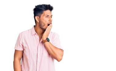 Gündelik tişört giyen yakışıklı Latin Amerikalı genç adam ağzıyla esnemekten sıkıldı. Huzursuz ve uykulu.. 