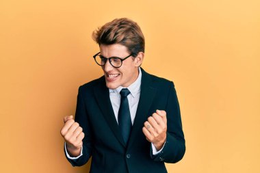 Yakışıklı, beyaz takım elbiseli, kravatlı, çok mutlu ve çok heyecanlı kolları havada, gülümseyen ve başarı çığlıkları atan bir adam. kutlama konsepti. 