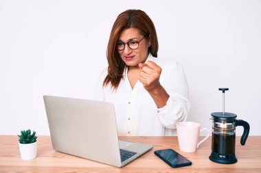 Orta yaşlı esmer İspanyol iş kadını ofiste çalışıyor öfkeyle bağırıyor, öfkeyle bağırıyor ve el kaldırıyor. 