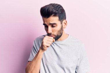 Sakallı, sıradan bir tişört giyen, kendini kötü hisseden ve soğuk algınlığı veya bronşitin belirtisi olarak öksüren genç yakışıklı bir adam. sağlık hizmeti kavramı. 