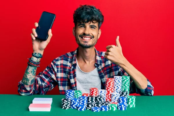 Jonge Spaanse Man Zit Tafel Met Poker Chips Kaarten Houden — Stockfoto