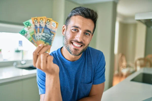 Jovem Bonitão Sorrindo Feliz Segurando Notas Dólares Australianos Casa — Fotografia de Stock